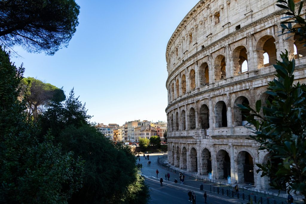 Capture of the iconic Colosseum in Rome with surrounding cityscape, framed by lush greenery.